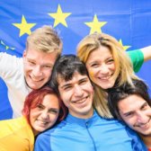 Fünf Europäerinnen und Europäer halten gemeinsam eine Europaflagge hinter ihren Rücken und sind fröhlich.