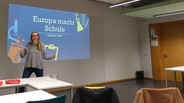 Eine junge Frau vom Standort-Team Mainz steht in einem Seminarraum und hält einen Vortrag zu dem Programm 