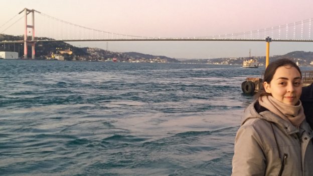 Frau Apkinar steht im Vordergrund. Im Hintergrund ist der Bosporus und eine Brücke zu sehen.