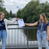 Die Zertifikatübergabe vom Standort-Team an eine Gaststudierende auf einer Brücke in Hamburg