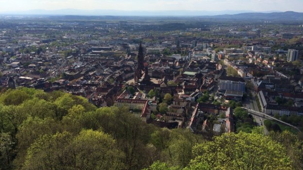 Blick auf Freiburg von oben. Häuser, Kirche, Bäume sind von oben zu sehen.