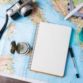 Eine Weltkarte mit einem leeren Block, einer Kamera, Kompass, Stift und Flugzeug sind zu sehen und laden auf ein neues Abenteuer ein.