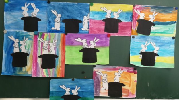 Die Schulklasse malte Papiere bunt an um Hasen eines Cartoons darauf zu kleben.