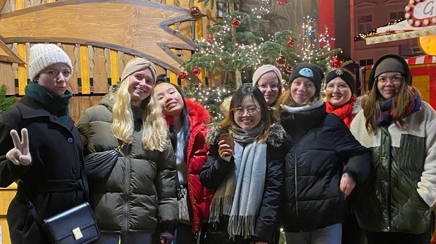 Ehrenamtliche des Programms Europa macht Schule stehen auf dem Christkindlmarkt in Regensburg und posieren vor einem Weihnachtsbaum