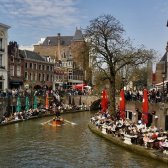 Utrecht fotografiert an einem sonnigen Tag mit Blick auf Fluss. Großes Gastronomieangebot am Ufer des Flusses mit vielen Besucherinnen und Besuchern.
