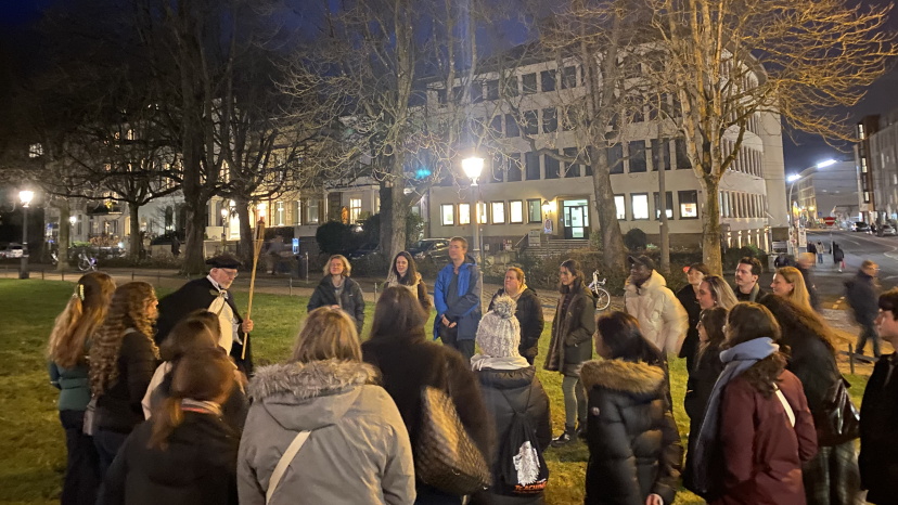 Gruppe von Menschen steht bei Nachtlicht um einen Erzähler.